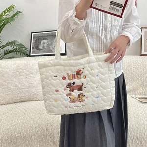 Detail of white quilted tote bag featuring cute dog embroidery and slogan text