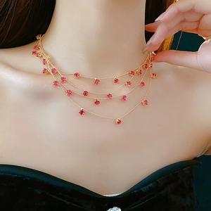 Gros plan d'un collier doré multicouche orné de multiples petites pierres rouges