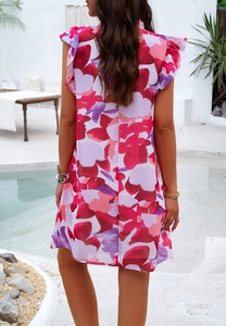 Vue arrière élégante de la robe à fleurs sans manches rouge et rose au bord de la piscine