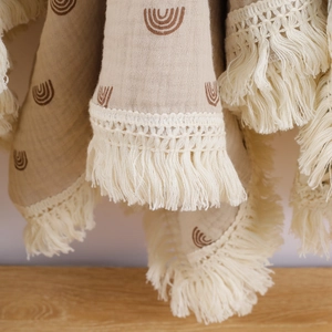 Muslin cotton baby blanket with brown rainbows, lace edges, and decorative tassels