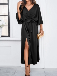 Detail view of black satin V-neck dress featuring high side slit and waist tie