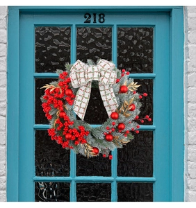 Detail of Christmas wreath with red berries, plaid bow and snow-tipped pine needles
