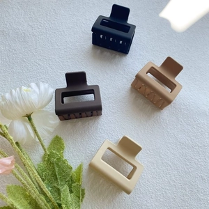 Detail view of four matte square hair claws in black, coffee, caramel and cream colors