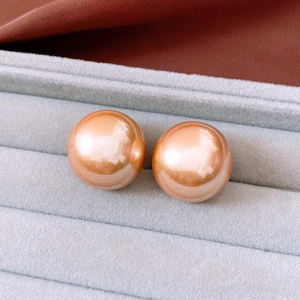Macro shot of large round orange-gold pearls on a gray velvet jewelry display box tray