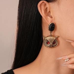 Macro view of vintage owl earrings with red gem eyes and black stone on model ear