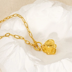 Elegant golden floral pendant necklace with OT toggle clasp on a textured stone base