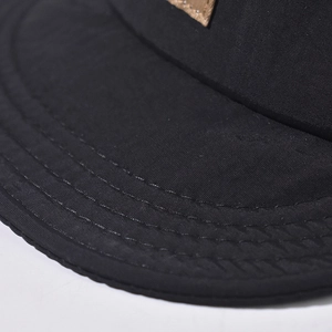 Detail of short brim hiking cap showing durable synthetic fabric and reinforced stitching