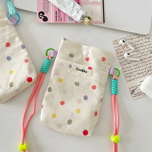 Detailed texture of polka dot canvas phone pouch with adjustable colorful woven strap