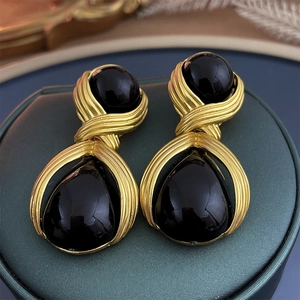Close-up of vintage dark acrylic drop earrings on a green leather surface