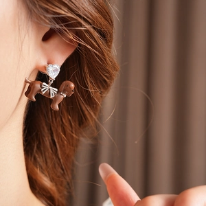 Detailed close-up of a puppy drop earring featuring a heart zircon and a brown bow-tie dog