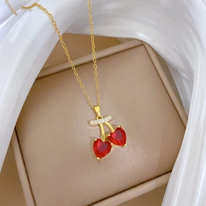 Detail of gold cherry necklace with red heart-shaped stones and pavé diamonds
