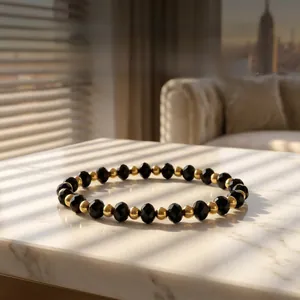 Close-up of 4mm faceted black amazonite beads and gold metal beads on marble surface