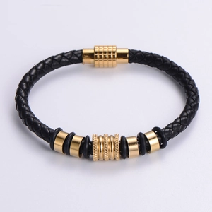 Dettaglio di bracciale in pelle intrecciata nera con perle dorate e chiusura magnetica