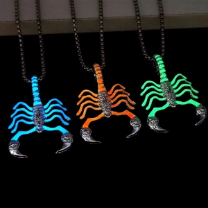 Luminous scorpion necklaces in blue, orange and green glowing against a dark background