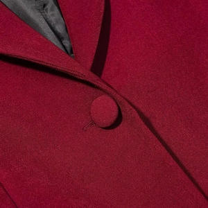 Detail of dark red blazer collar with matching fabric button and textured weave