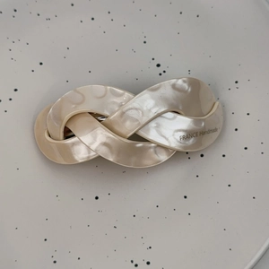 Detailed macro of cream pearl-finish twist hair clip with FRANCE Handmade engraving