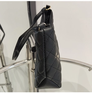 Side view detail of black quilted bucket bag featuring gold hardware and PU leather texture
