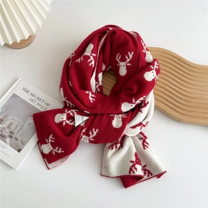 Close-up of red and white knit scarf featuring reindeer pattern on a wooden board