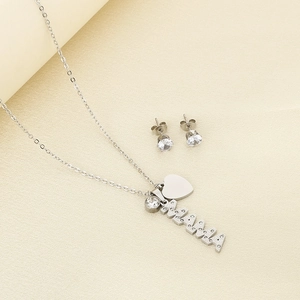 Macro view of silver MAMA heart pendant necklace and zircon earrings set on beige fabric
