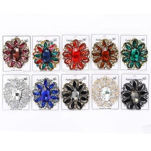 Flat lay of floral rhinestone brooches in multiple vibrant colors with metal base