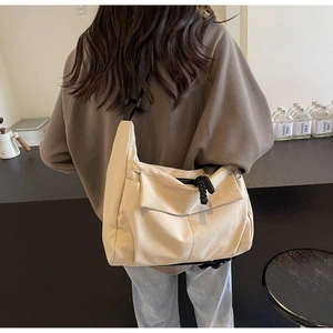 Detail view of cream-colored canvas tote bag worn as a shoulder bag with adjustable strap