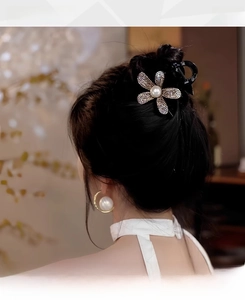 Detail of elegant black hair claw clip with crystal flowers and pearl embellishment