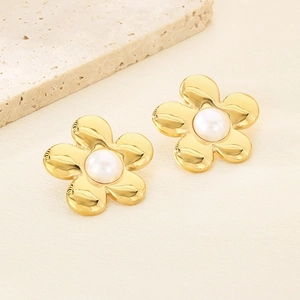 Détail de boucles d'oreilles fleur en acier doré 18K avec perle sur une pierre