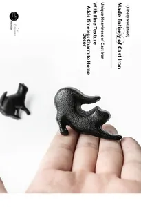 Detailed close-up of a matte black cast iron cat-shaped drawer handle in hand