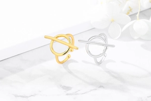 Detail geometrischer offener Ringe in Gold und Silber auf weißem Marmorhintergrund