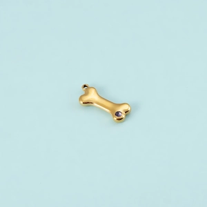 Close-up of golden dog bone pendant with purple zircon inlay for DIY jewelry design