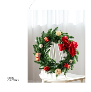 Christmas wreath with red velvet bow and bus charm leaning on a white wooden chair
