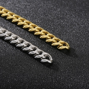 Macro shot of gold and silver stainless steel curb chain bracelets with lobster clasps