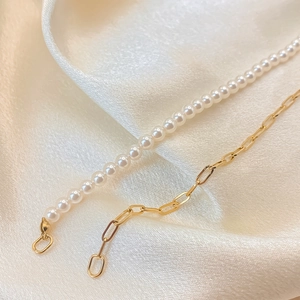 Elegant gold paperclip chain necklace with white faux pearls on silk background