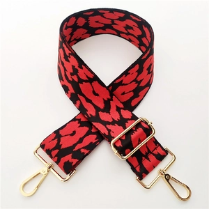 Close-up of a wide leopard print bag strap with red and black pattern and gold hooks