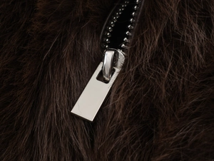 Detail of silver metal zipper on a dark brown faux fur vest with soft plush texture