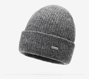 Close-up of grey knitted beanie featuring thick texture and metallic brand logo plate