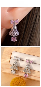 Macro detail of sweet bow bell earrings with pink and clear zircon stones in titanium steel