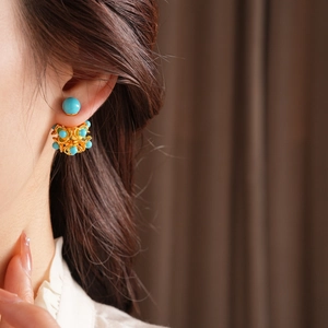 Détail de boucles d'oreilles fleurs en résine dorée avec perles turquoise style modulable