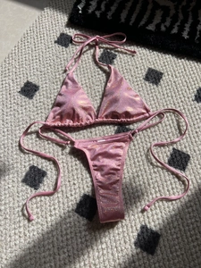 Flat lay of pink glitter bikini set showing triangle top and strappy thong bottoms