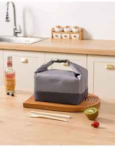 Detail of insulated lunch bag with buckle handle on a wooden tray in kitchen setting