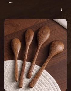 Detailed view of four handcrafted long-handle wooden spoons with natural grain texture