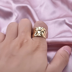 304 stainless steel gold hammered wide ring on hand with elegant pink silk background