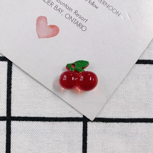 Detailed view of red acrylic cherry pendants with green leaves for DIY jewelry making