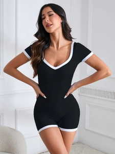 Seamless black yoga bodysuit with white contrast piping and ribbed waist compression