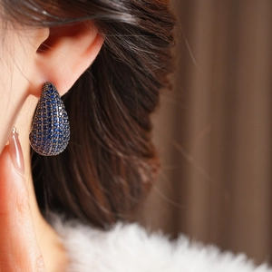 Close-up of vintage water-drop earrings with pavé-set deep blue cubic zirconia on model