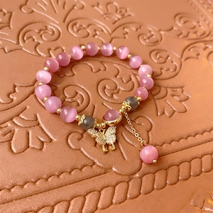 Détail du bracelet en perles œil de chat roses avec pendentif papillon serti de cristaux