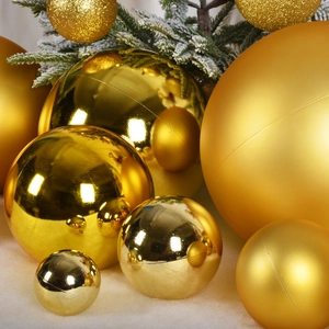 Golden Christmas baubles in shiny matte and glitter finishes on snow with pine branches