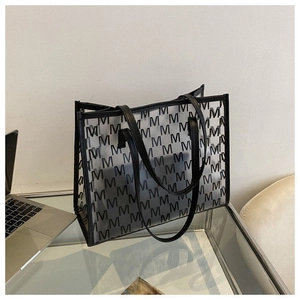 Detail of large transparent tote bag with black and white M-pattern on office desk