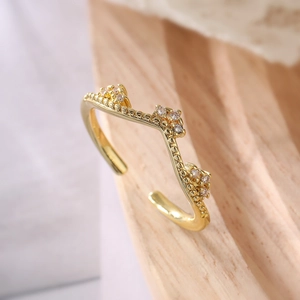 Adjustable gold-plated crown ring featuring sparkling cubic zirconia on a light wood surface