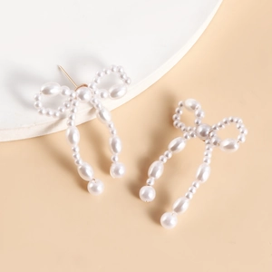 Detailed macro view of woven white pearl bow earrings with long elegant drop tassels